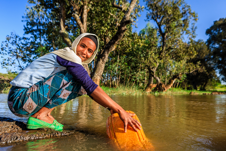 Woman taking water out of a river in Ethiopia